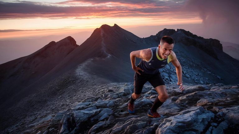 Trail runner ascending rocky mountain terrain at sunset during altitude training