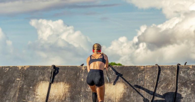 Athlete climbing a wooden traverse wall obstacle during OCR training
