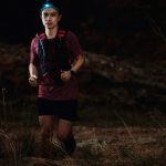 Trail runner with headlamp running on a rocky night course