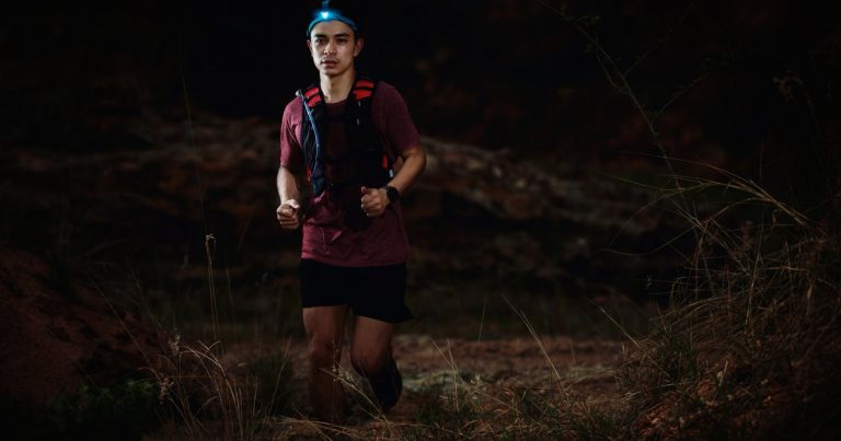 Trail runner with headlamp running on a rocky night course