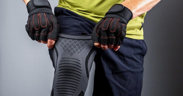 Athlete putting on knee support brace and compression sleeve for sports protection