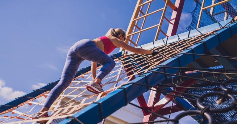 Athlete climbing a cargo net obstacle at an outdoor training camp