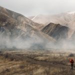 Runner on trail with dramatic mountain range backdrop, representing destination OCR race venues