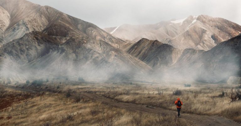 Runner on trail with dramatic mountain range backdrop, representing destination OCR race venues