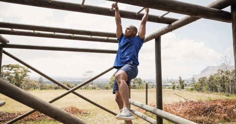 Athlete climbing monkey bars on an obstacle course