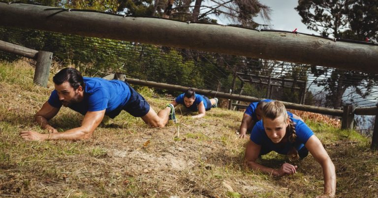 OCR athletes crawling under a net obstacle during a race
