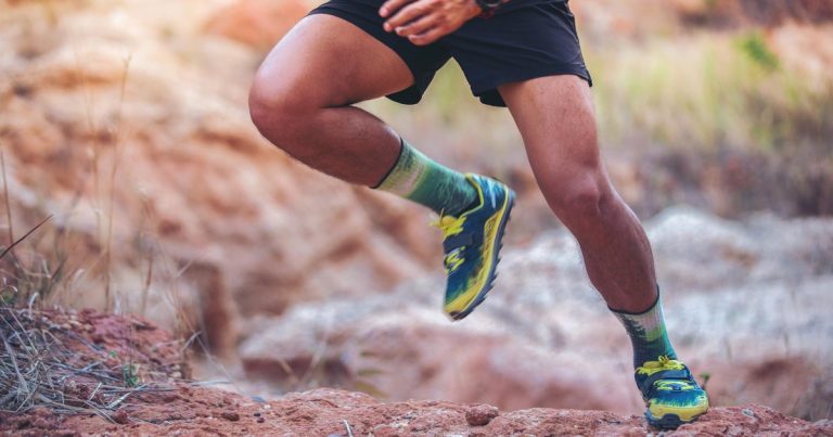 Trail runner in athletic socks and race shoes on rugged terrain