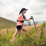 Trail runner using trekking poles on mountain terrain