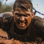 Runners competing in a muddy obstacle course race