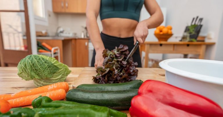 Athletic woman preparing plant-based meal with fresh vegetables for sports nutrition