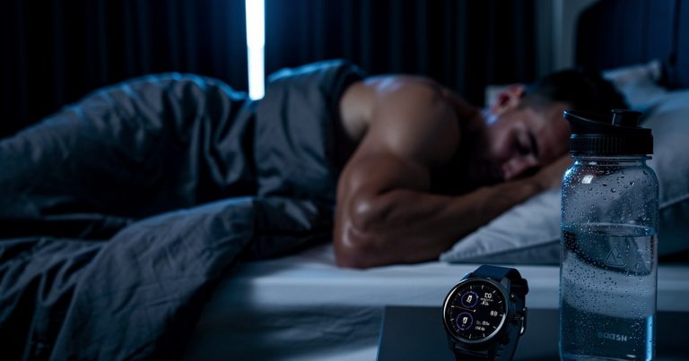 Athlete sleeping for recovery in a dark cool bedroom with sports watch on nightstand