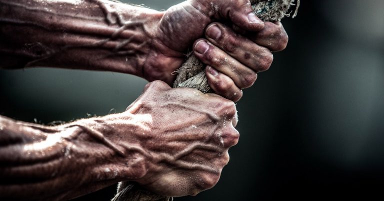 OCR athlete gripping rope obstacle showing tendons and forearm muscle under load