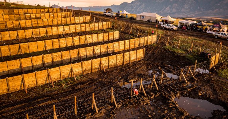Aerial view of an OCR event venue with obstacles and safety infrastructure at golden hour