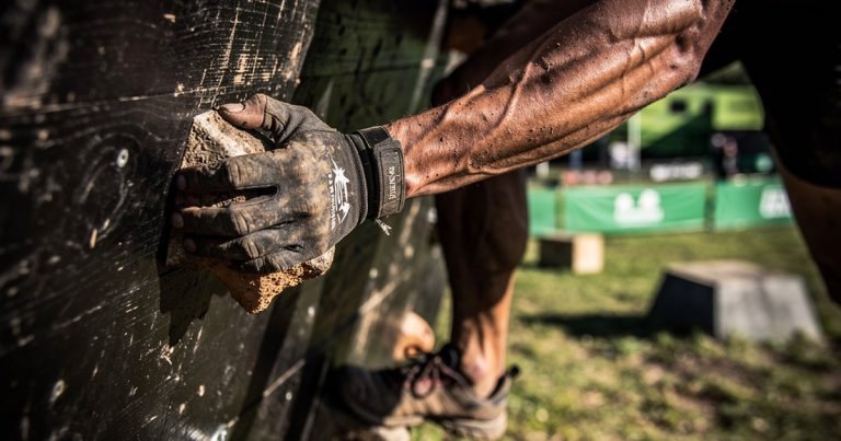 OCR athlete gripping a traverse wall obstacle during a race