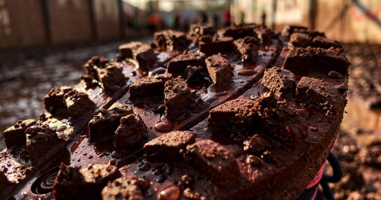 Close-up of aggressive OCR shoe lugs caked in mud on a race course