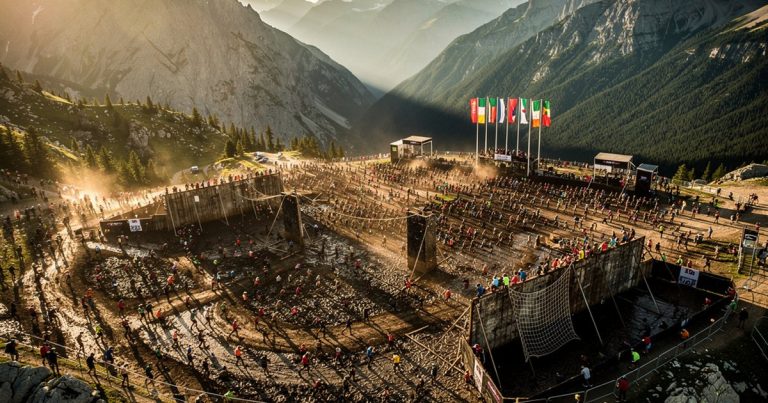 OCR athletes racing across a dramatic international mountain course at golden hour