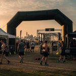 OCR race festival grounds with athletes and sponsor activation tents at dusk